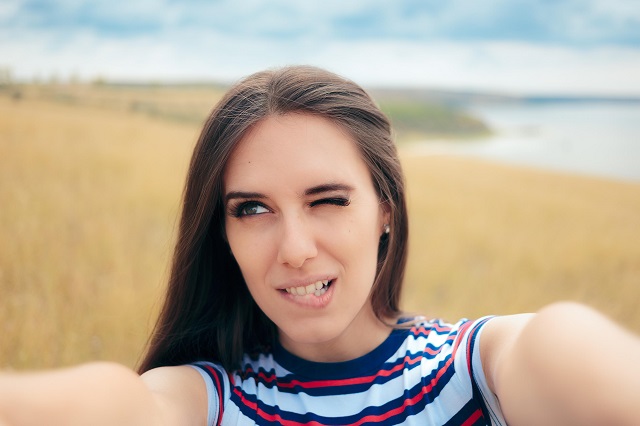 Zdjęcie selfie modelki na polu nad jeziorem